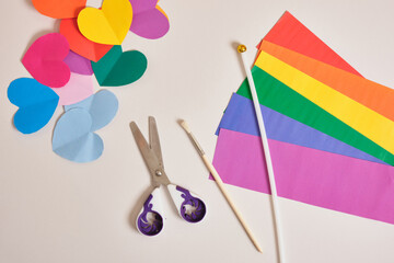 scissors, stripes of paper in the colors of lgbt community flag and rainbow colored paper hearts, lgbt concept