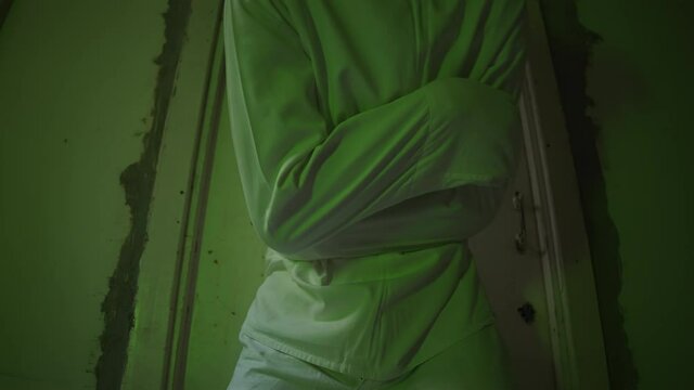 A mad male patient in straitjacket is going crazy in a mental hospital. Close up of mentally ill man with psychic disorders and bipolar disease. Concept of paranoia or schizophrenia and madness.