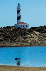 El faro de Favaritx con un pequeño lago de agua de mar en la parte delantera.