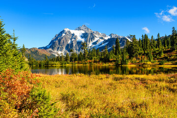 Mount Shuksan rising behind Picture Lake with a foreground of bright fall colors and under a blue sky