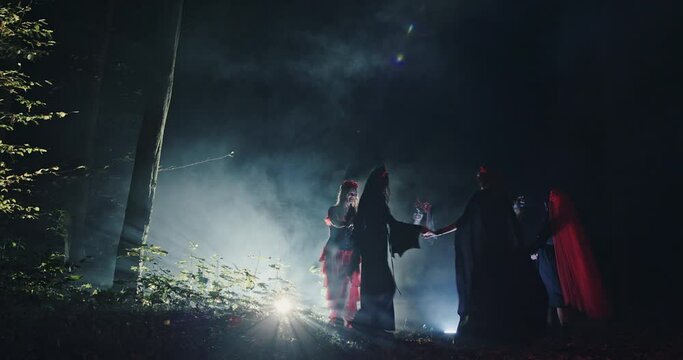Sabbath witches whirling their hands at night in the woods in the smoke conjure up evil spirits magic abused