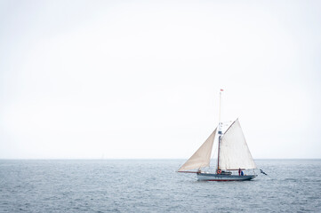 sailing boat on the sea sailing on the horizon there are two fishermen on it.