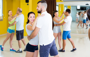 Fototapeta na wymiar Positive men and women dancing salsa in dance hall