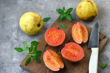 Guava fruit or Psidium Guava on wooden chopping board , on grey grainy background. 