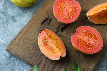 Guava fruit or Psidium Guava on wooden chopping board , on grey grainy background. 