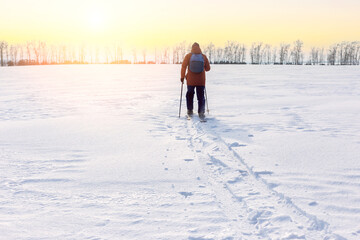 A man with backpack on skis  in snowy field. Freedom, adventure concept. Loneliness.