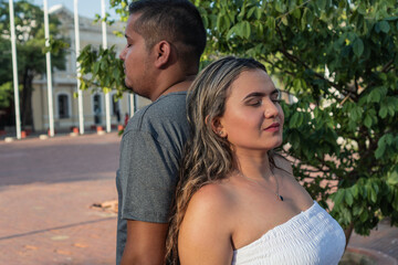 Hispanic couple with their backs to each other with their eyes closed