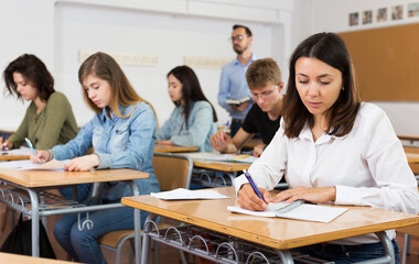 Fototapeta premium serious schoolgirl is sitting test and answer about task in the classroom.