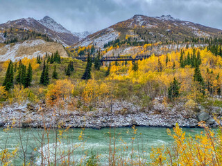 A Beautiful Scene of the River, Lightly Snow-Covered Mountains, Fall Foliage, and Train Bridge in Healy, Alaska 