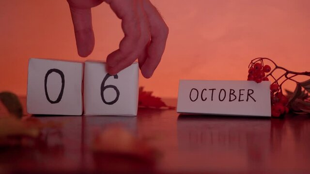 Cube calendar with an important date of October 6th with maple leaves and berries on the desk. Autumn Season.