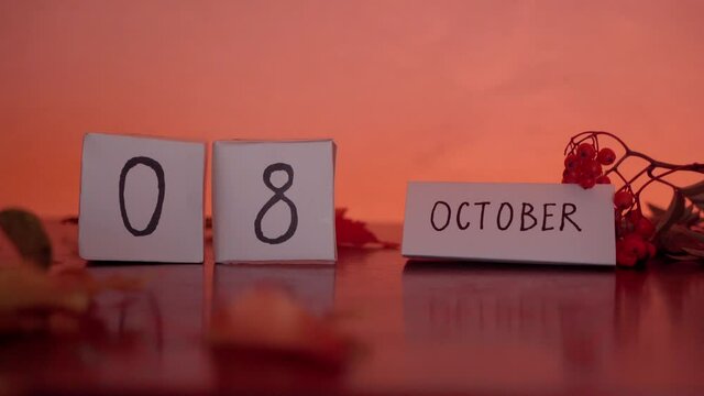 Cube calendar with an important date of October 8th with maple leaves and berries on the desk. Autumn Season.