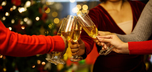 Beverage glasses clinking moment by cheerful woman friends on sweater as enjoy celebrating happy...