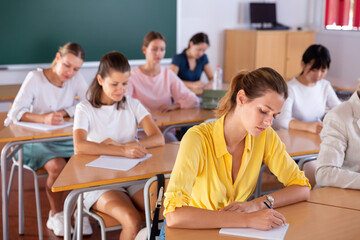 Multiracial female group of students writing at desk in classroom at university