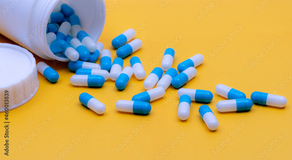 Wall mural pour capsule pills out of plastic bottle. capsule pills on yellow background. prescription drugs. ph