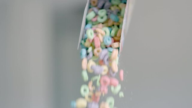 Breakfast cereals in the form of colorful corn rings are poured out of the package. Food close - up of Colored corn flakes and dairy products. Slow motion. High quality 4k footage