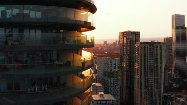 Crane up footage of balconies around Arena Tower apartment complex. Backlit by setting sun. London, UK