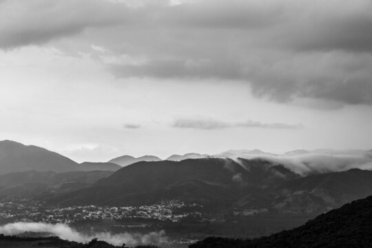 Dramatic black and white image Caribbean mountains after a storm in the Dominican Republic, with foggy cloudy skies and fading hills in background 