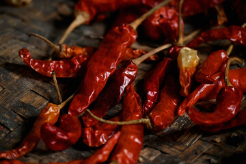 closeup the bunch red ripe dried chilly in the wooden basket over out of focus brown background.