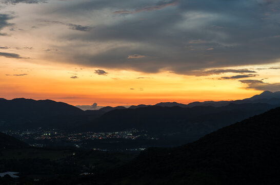 Dramatic sunset image of the Caribbean mountains with a small town with street lights in the Dominican Republic.