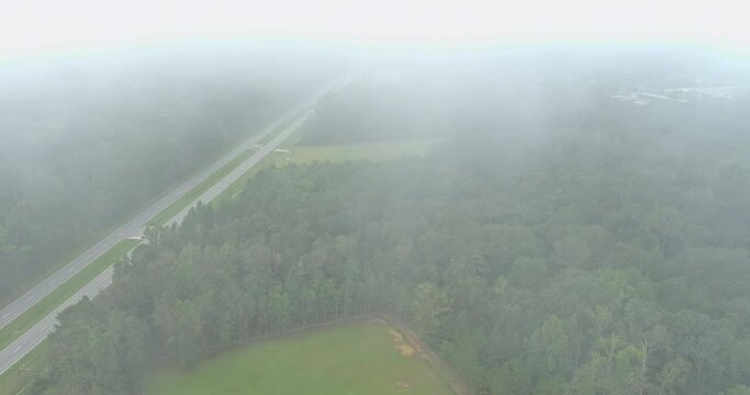 Aerial view beautiful early morning with low hanging fog looking over a meadow near highway US 43in Satsuma, Alabama US