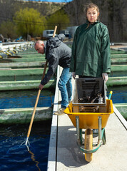 Male and female fish farm workers catching sturgeon at pools