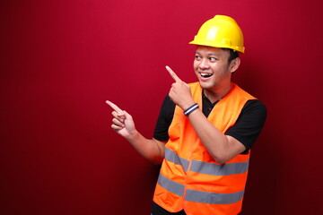 Smile and happy young asian man worker is with with hand point on empty space