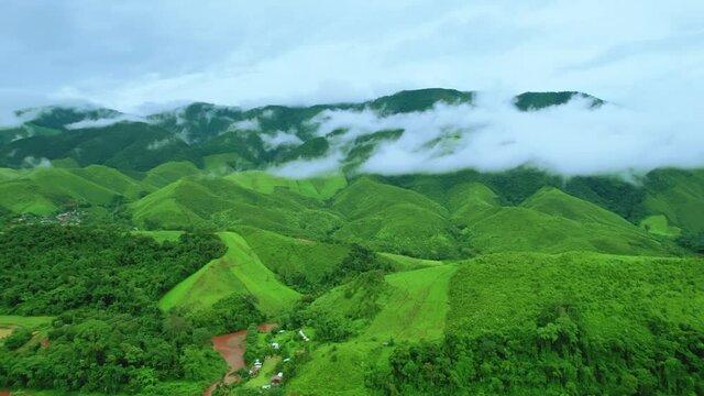 Aerial view drone shot of flowing fog waves on mountain tropical rainforest In the evening,Bird eye view image over the clouds Amazing nature background with clouds and mountain peaks.