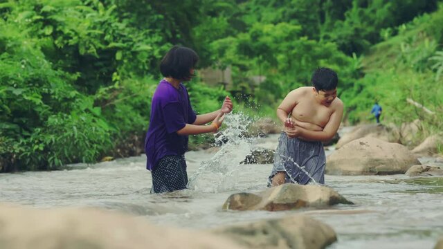 Children playing with friends in the river in countryside, Boys and girls smiling and happiness playing water at the countryside in Thailand.