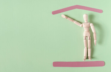 A wooden figure of a man with a raised hand and red frames symbolizing protection. The concept of protection of the population, social problems.