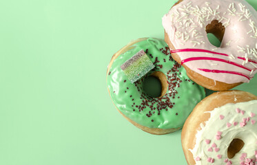 Fresh donuts with colored glaze on a green background of the mine space. Colorful donuts close-up