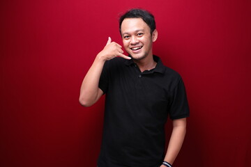 Smiling young asian man with talk or call gesture hand