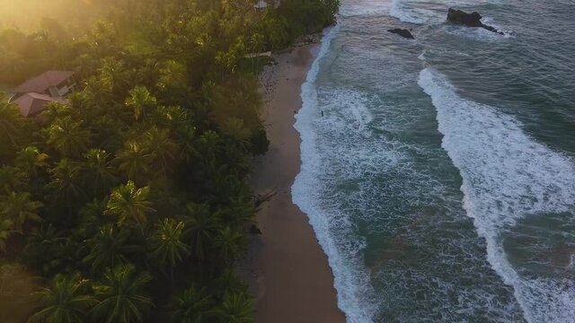 Waves Crashing along the shoreline at sunset aerial view