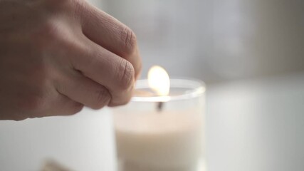 Slow motion of hand lighting up white candle with matchstick inside home for dinner,close up