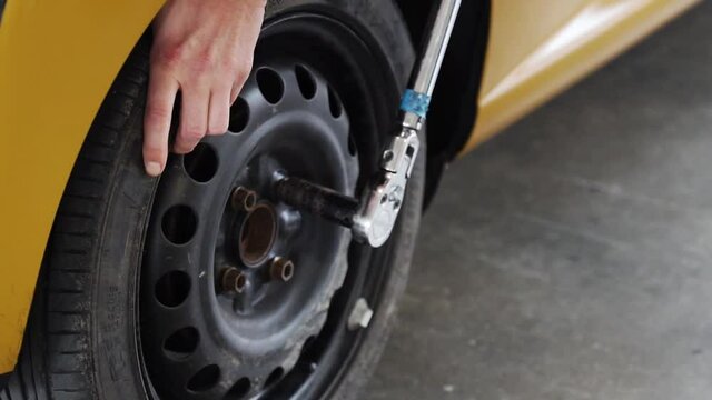 Mechanic tightens wheel nuts on race car with wrench