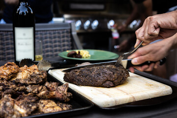 Cutting meat for friends wtih a bottle of Cooper Vineyards wine