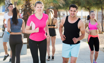 People leading healthy lifestyle, jogging during outdoor workout on city seafront