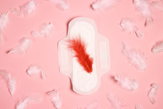 Menstrual pad with red and white feathers on pink background.