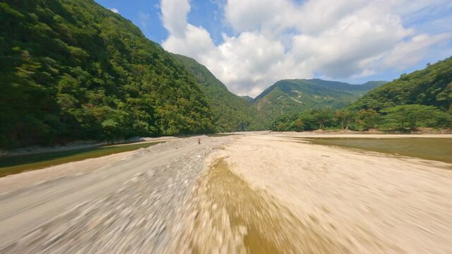 Aerial flight over dried river bed between green mountains in summer - Muchas Aguas in Dominican Republic