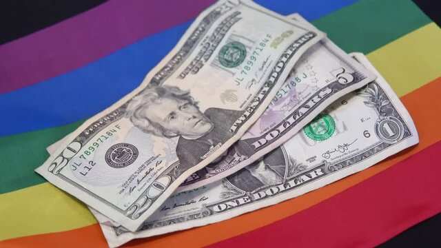 colorful waving gay flag on a american dollar money in front
