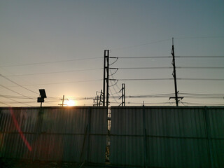 Corrugated Metal Fence with Utility pole in sunset time, electric wire floating in overhead