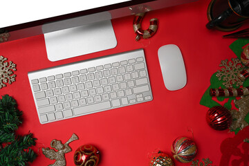Computer on red background with Christmas decorations.