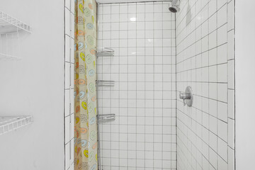 Small tiled shower in empty white bathroom