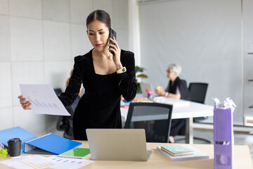 Smiling  Asian entrepreneur woman busy working talking on mobile phone in home office. Banner background copy space