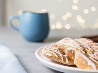 Cinnamon roll or cinnamon bun Dessert on plate with blue cup of coffee. Classic American or French bakeries. Bokeh