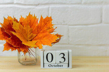 October 3 on the calendar and a bouquet of bright autumn leaves on the table.One of the days of the...