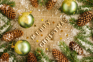 Christmas traditional background with Christmas balls, cones and branches of spruce. laid out wooden letters, with a wish for a Merry Christmas.