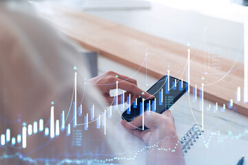 A woman trader holding in the hands a smart phone and researching stock market to proceed right...