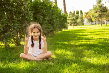 Naklejka na ściany i meble Portrait of a cute nine-year-old girl showing the rock sign. Space for text.
