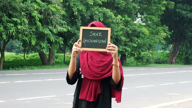 Kolkata, India : Attractive Afghan woman in hijab with a black sign board in her hands with written save Afghanistan