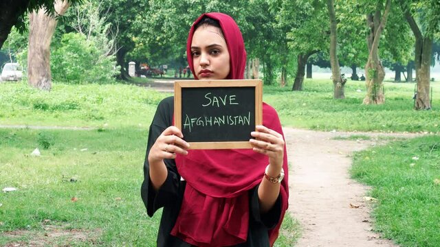 Kolkata, India : Attractive Afghan woman in hijab with a black sign board in her hands with written save Afghanistan, on a black background. Taliban Afghanistan war 2021,save Afghanistan.